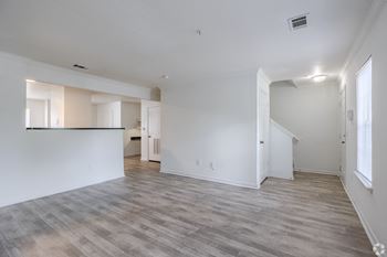 an empty living room and kitchen with white walls and wood flooring at Greens at Stonecreek, Lithonia, Georgia